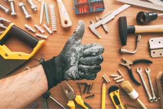 Handyman gesturing a thumbs up above tools that are laid out on the table